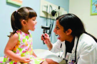  a doctor checks a young girl's mouth
