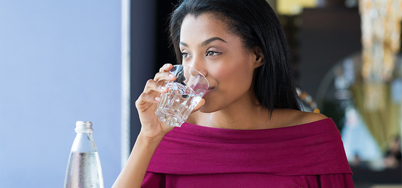 A woman drinks from a glass of water